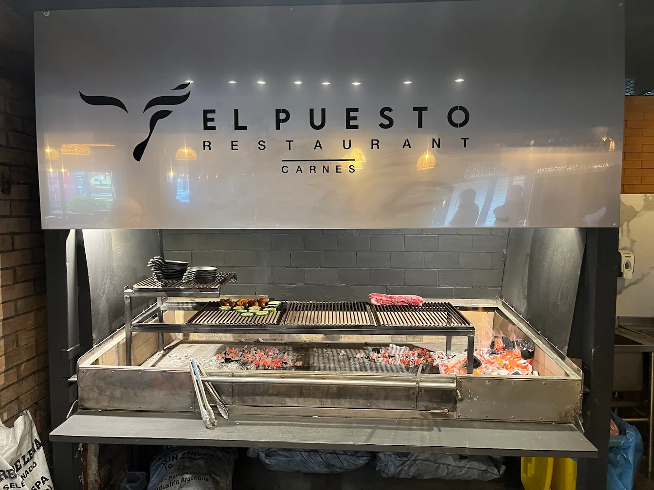 Interior de El Puesto Restaurant con parrilla al fuego vivo en Puerto Varas